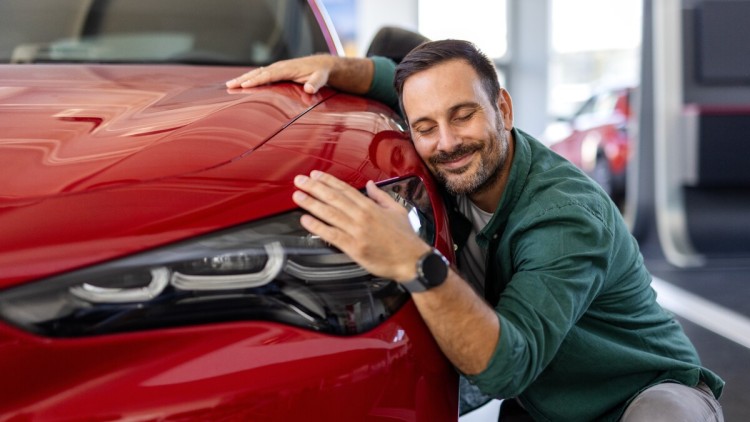Mann umarmt sein neues Auto